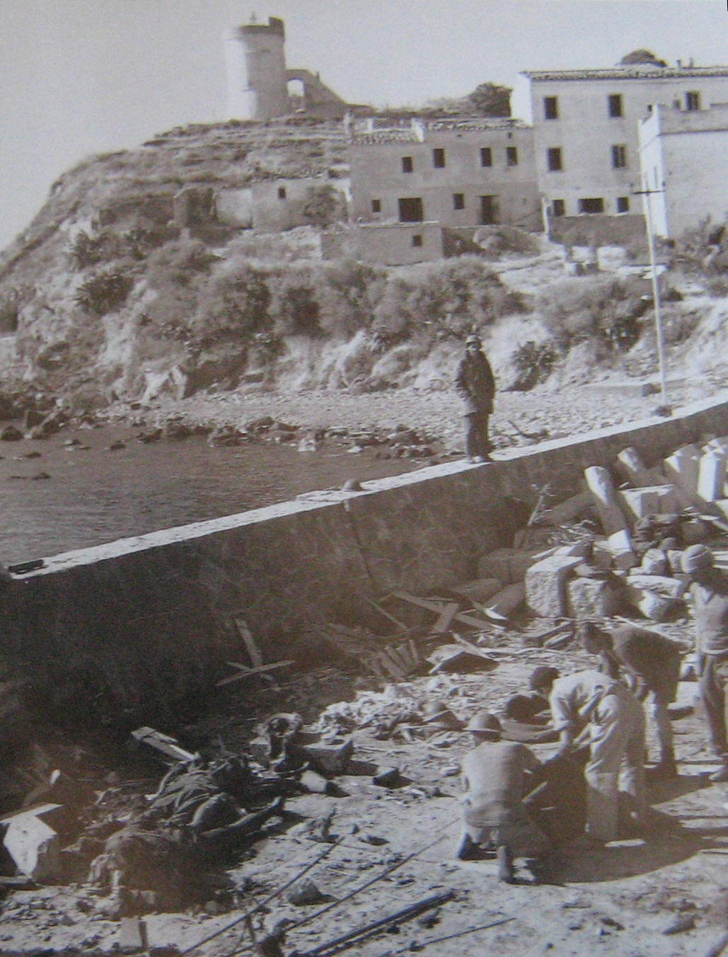 Marina di Campo dopo la battaglia.Sullo sfondo la Torre con dietro la postazione della Breda 20/65.A sinistra sulla scogliera si intravede la bocca di balena